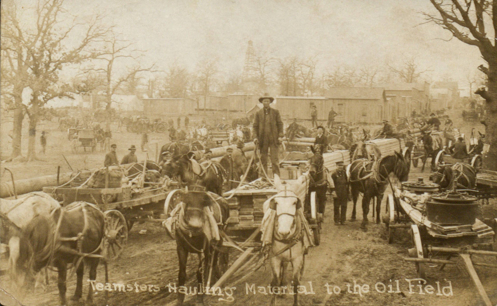 A grou of horses and wagons with oil fields in background