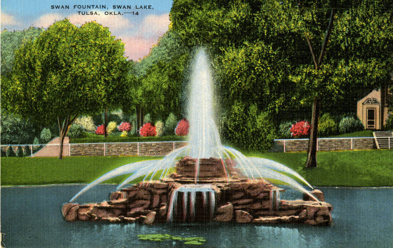 Beautiful, colorful fountain with water jets shooting into the sky. It is made of rock and sits on top of the lake